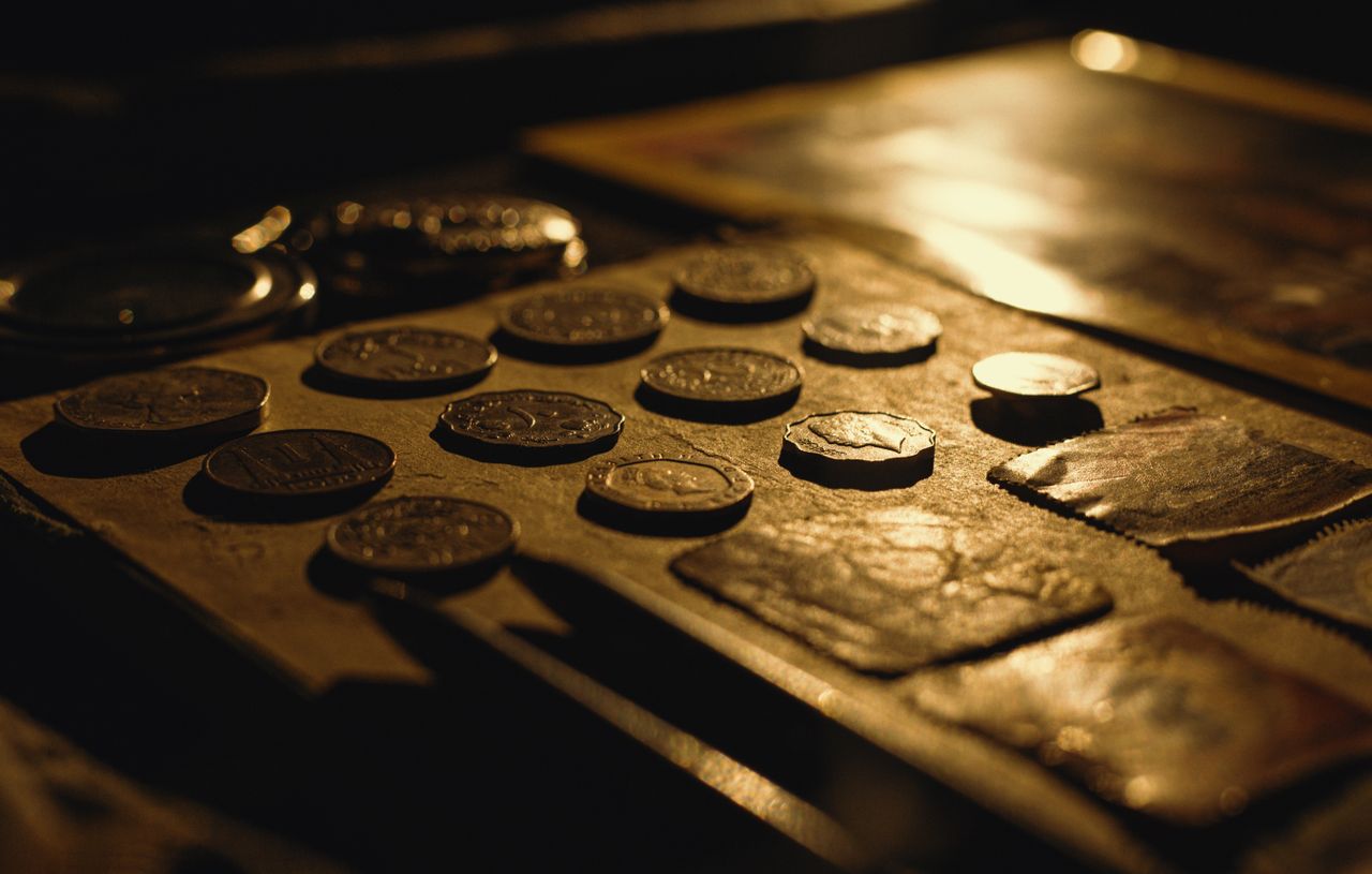 Close-up of antique coins on a table, captured with dramatic lighting and rich textures.